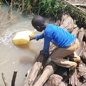 A boy gathering dirty water.  Lack of access to clean water is a crisis.