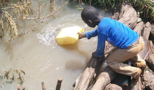 Boy collects dirty water in Uganda.